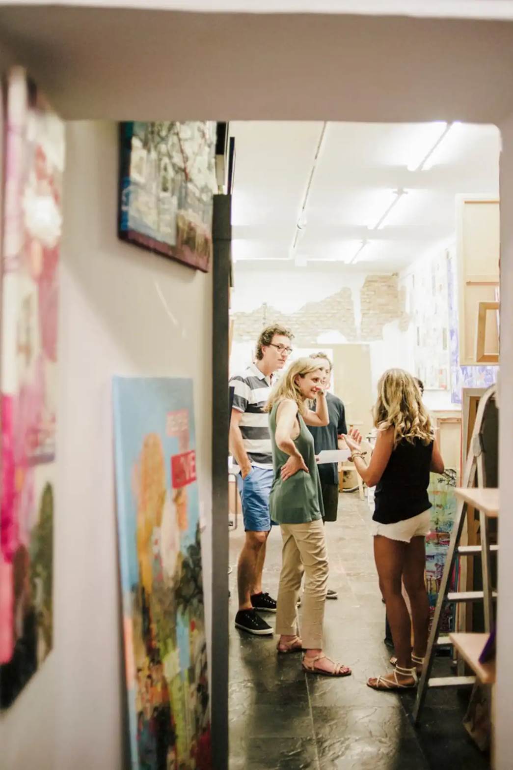 A group of people in an art studio discussing.