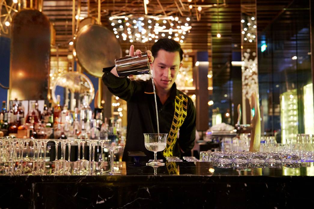 A bartender pouring a drink at SEEN Restaurant & Bar Bangkok.