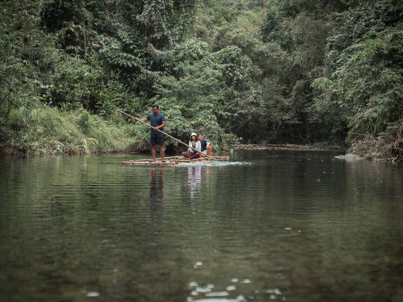 People on a bamboo raft floating in the jungle river