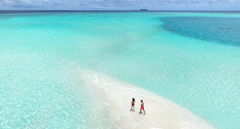 Couple walking on the sandbank at Avani+ Fares Maldives Resort