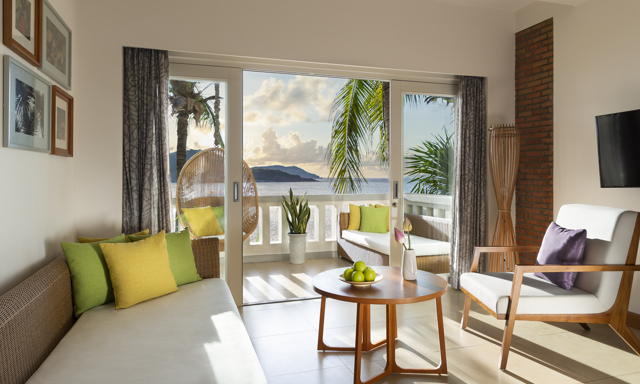Interior view of lounge in Avani Junior Ocean Suite with view of ocean from private balcony 